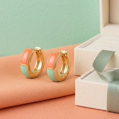 Angled front view of coral and mint earrings on apricot fabric